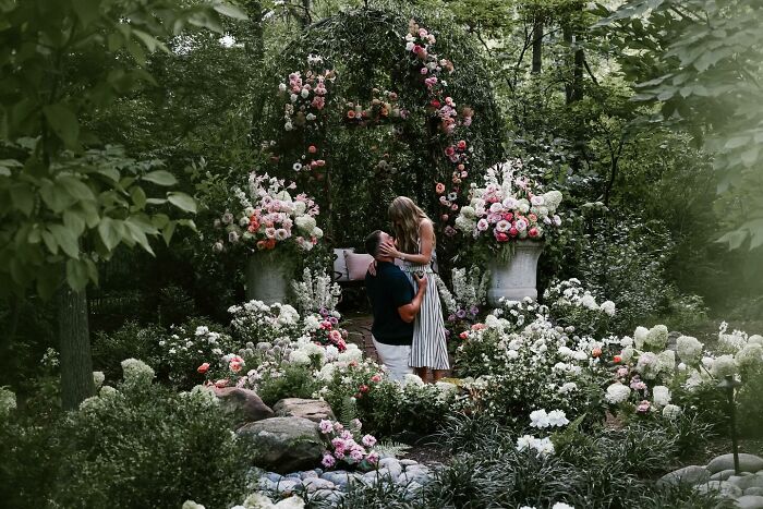 Couple sharing a romantic moment in a lush garden surrounded by flowers, highlighting Travis Kelce&rsquo;s ex Kayla Nicole buzz.