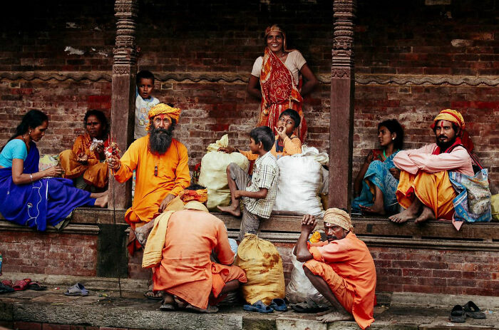 Group of people in traditional clothing sharing candid everyday moments captured by photographer in Asia setting.