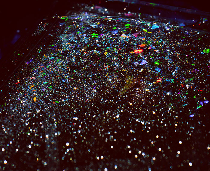 Close-up of colorful glitter scattered densely across a dark surface, highlighting glitter in car damage context.