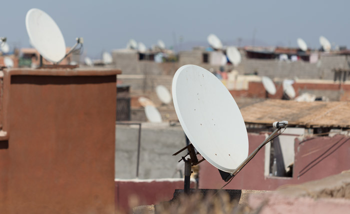 Satellite dishes on rooftops in a residential area, illustrating experiences of professionals who work in other people’s homes.