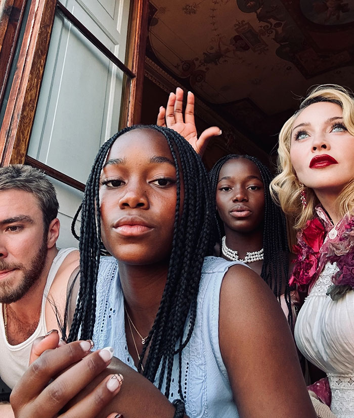 Lourdes, Madonna's daughter, with braided hair and friends at a party, captured in a close selfie indoors.