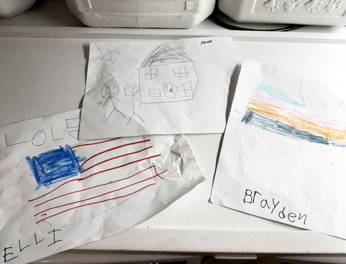 Children's drawings of a house, flag, and colorful abstract lines, reflecting wholesome kind neighbors and community spirit.
