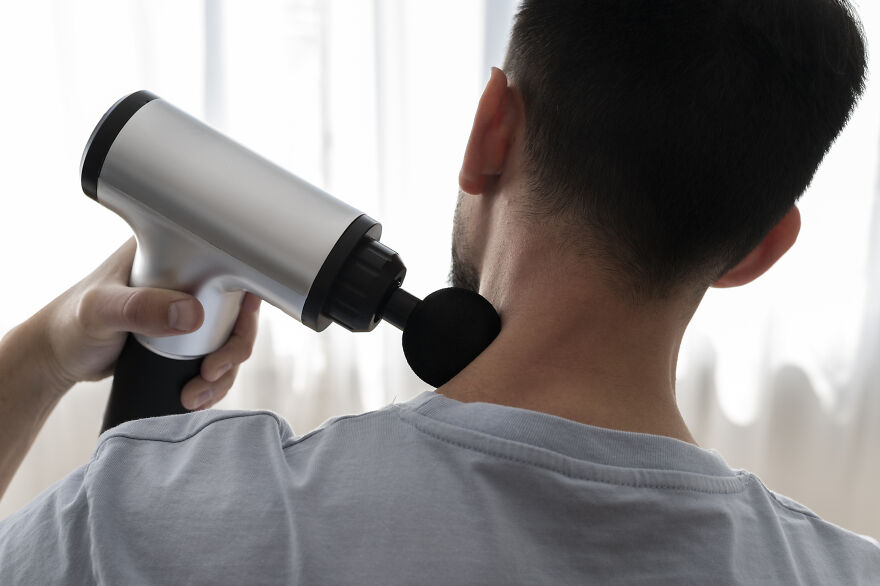 Man using a massage gun on neck after exercise, highlighting neurologist warning about post-exercise habits and stroke risk