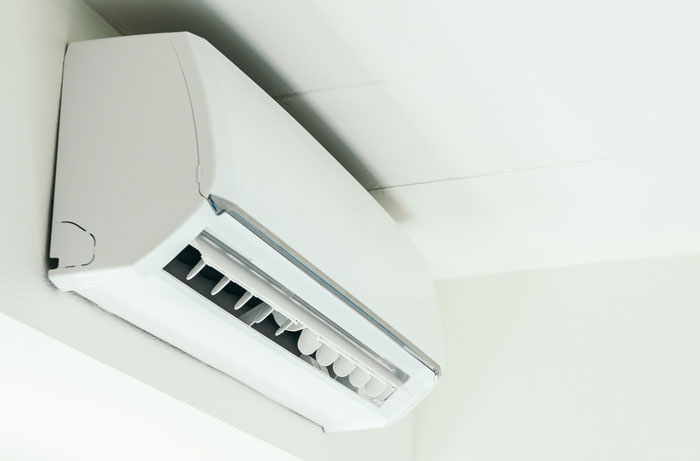 Wall-mounted air conditioner unit operating inside a room, symbolizing AC refusal and illegal activities by roommates.