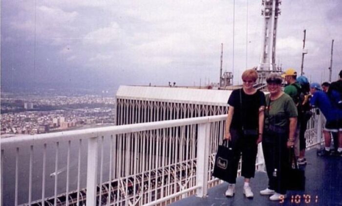 Two people standing on a rooftop deck overlooking a cityscape with cloudy skies in unsettling morbid knowledge image.