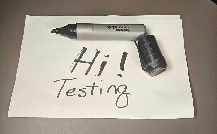 Back to school finds marker with black ink writing Hi Testing on white paper on a gray surface