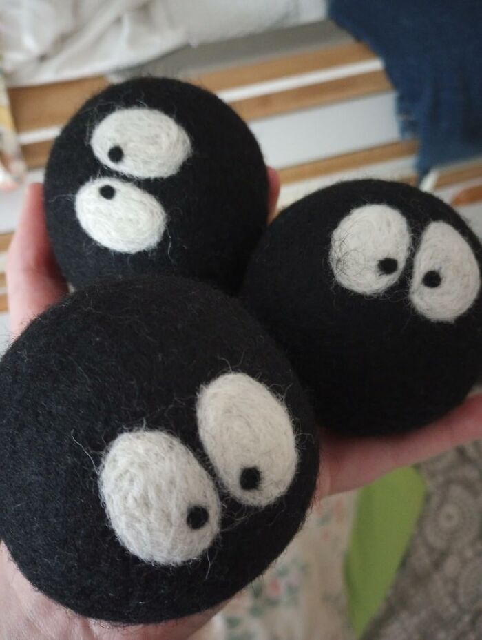 Hand holding three black felt balls with white eyes, showcasing fun and functional creative finds for home or play.