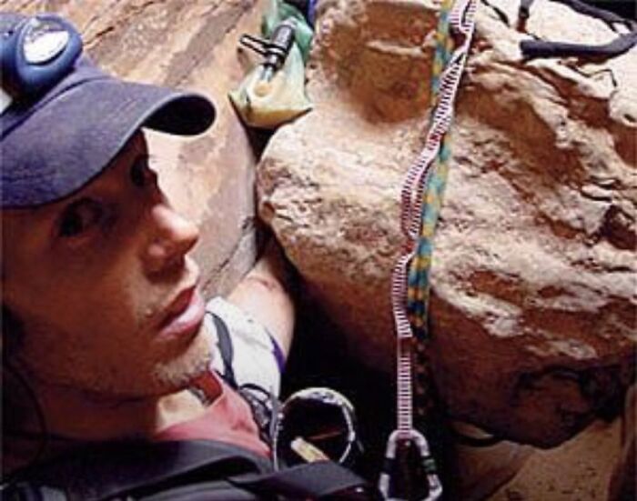 Man wearing a cap and climbing gear ascending rocky terrain, an example of unsettling images from morbid knowledge online group.