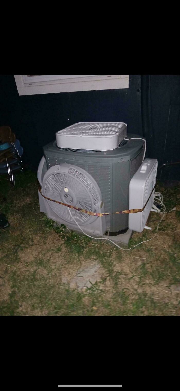 DIY cooling system made with multiple fans strapped to an air conditioning unit showing redneck engineer ingenuity outdoors at night