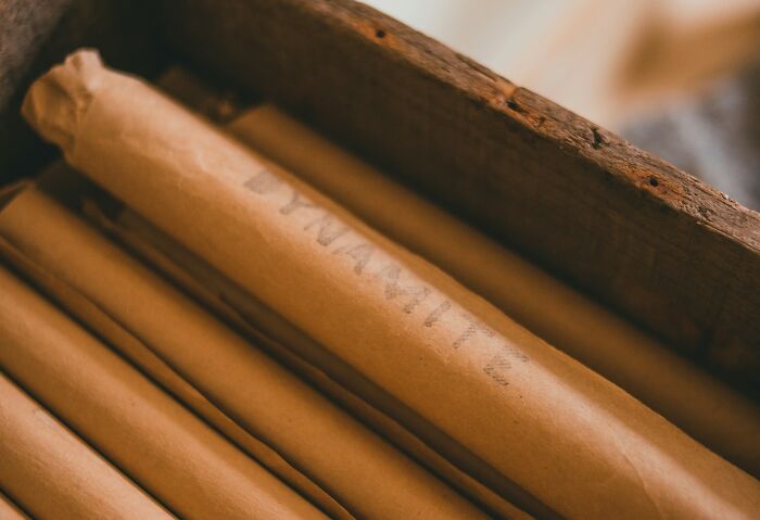 Rolled vintage documents in a wooden box representing ingenious inventions repurposed over the years.