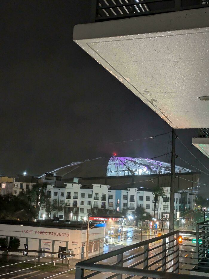 Night cityscape with wet streets and illuminated buildings under dark clouds, showing wild pics of mother nature.
