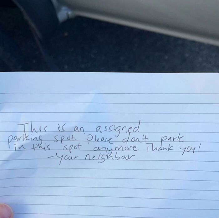 Handwritten neighbor's note warning against parking in an assigned spot, showcasing unhinged neighbors' notes humor in daily life.