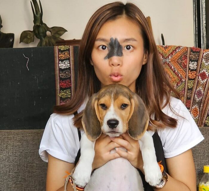 Woman with a unique birth mark on her nose holding a beagle puppy, showcasing interesting birth marks and pet companionship.