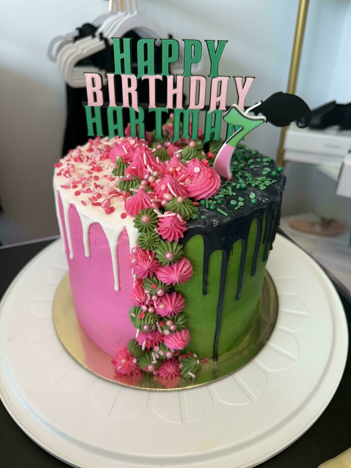 Colorful birthday cake with pink and green icing, floral decorations, and dripping frosting showcasing gorgeous baked goods artistry.