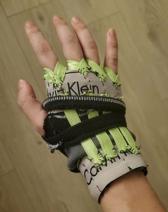 Hand wearing a homemade fingerless glove with green ribbon stitches, showcasing redneck engineering creativity and invention.