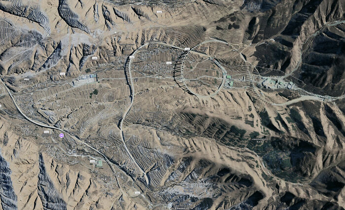 Aerial view of brilliant infrastructure showcasing complex terraced landscape and road networks in a mountainous region.