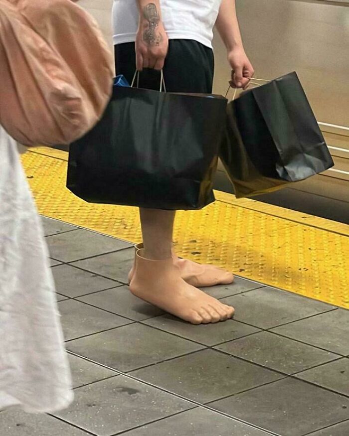 Person wearing realistic foot slippers and holding black shopping bags, a funny example of awful taste but great e*******n.