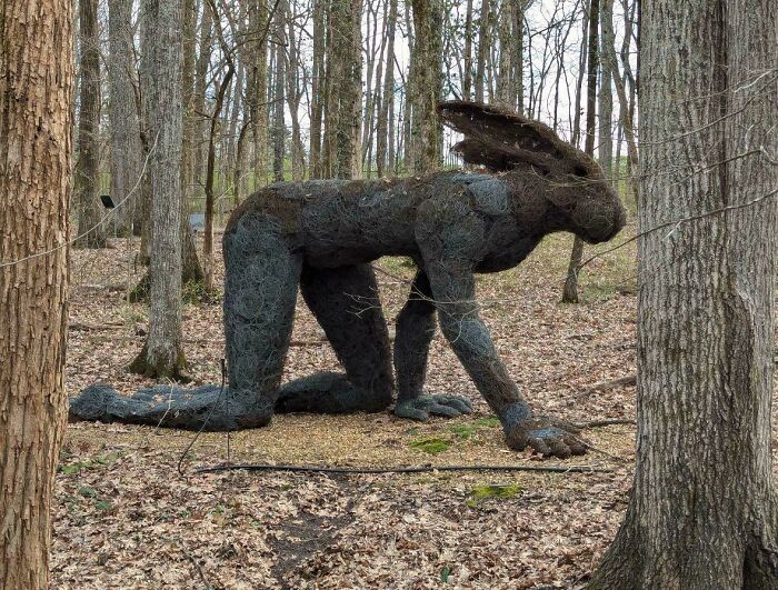 Large wire sculpture of a hare on all fours in a wooded area, showcasing an example of awful taste but great e*******n.