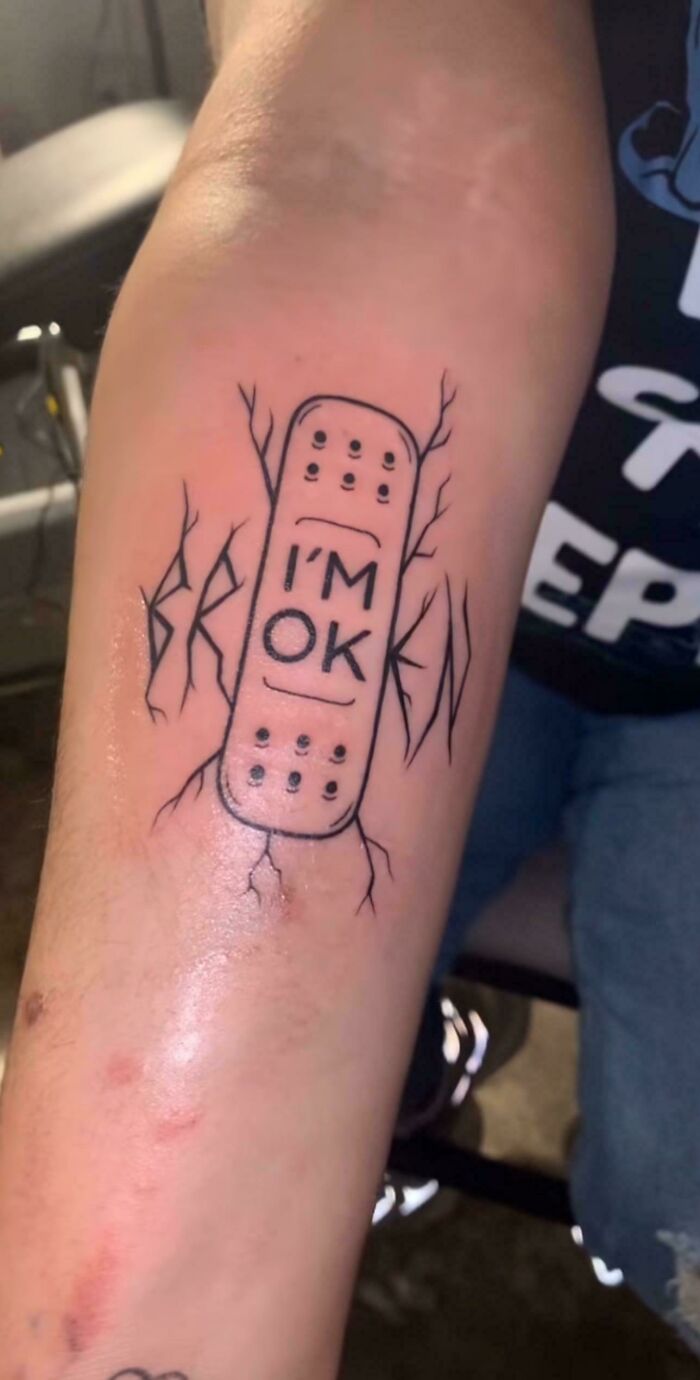 Tattoo of a bandage with "I'm OK" text and "broken" word in c*****d design showing awful taste but great e*******n.
