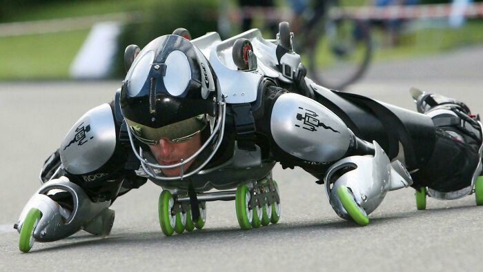 Person wearing a robotic suit with rollerblade wheels lying flat on a pavement, showing fun examples of awful taste.