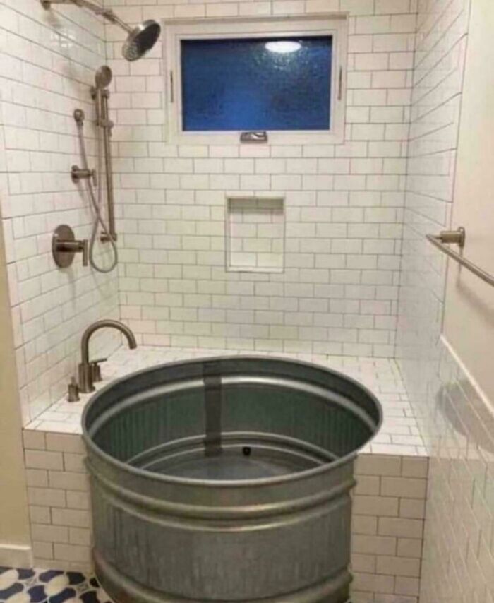 Bathroom shower with a metal tub placed inside a tiled shower area showing awful taste but great e*******n design.