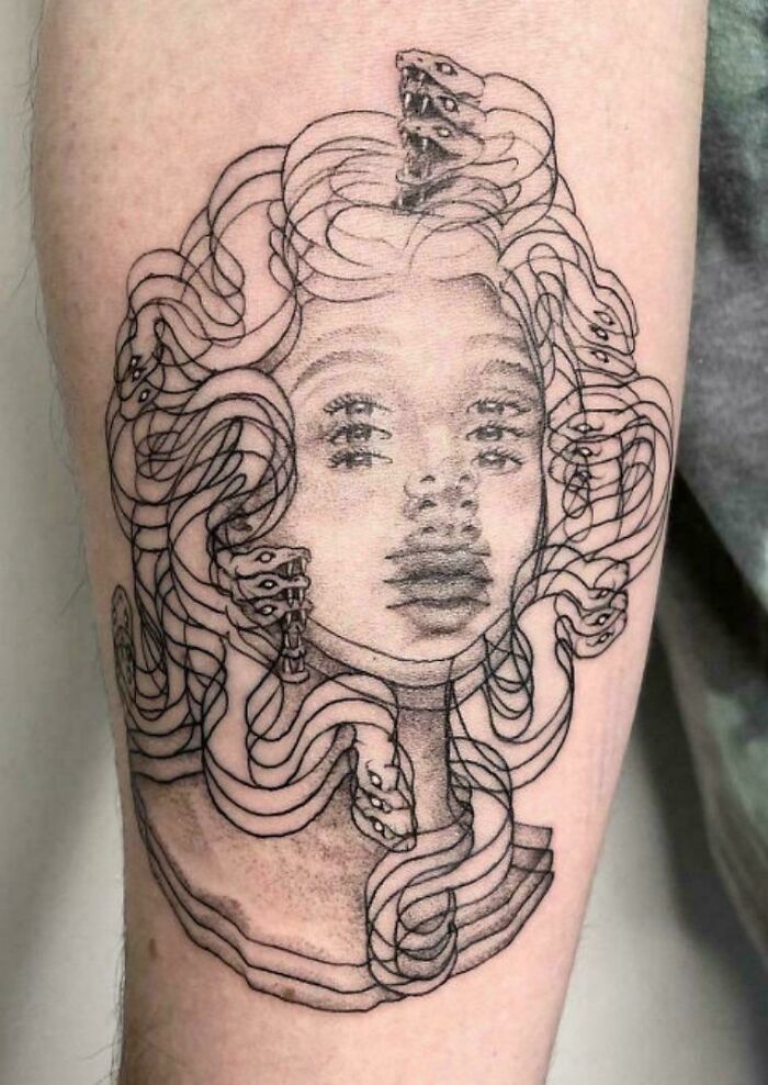 Tattoo of a distorted Medusa head with multiple eyes and overlapping snake hair, showing awful taste but great e*******n.