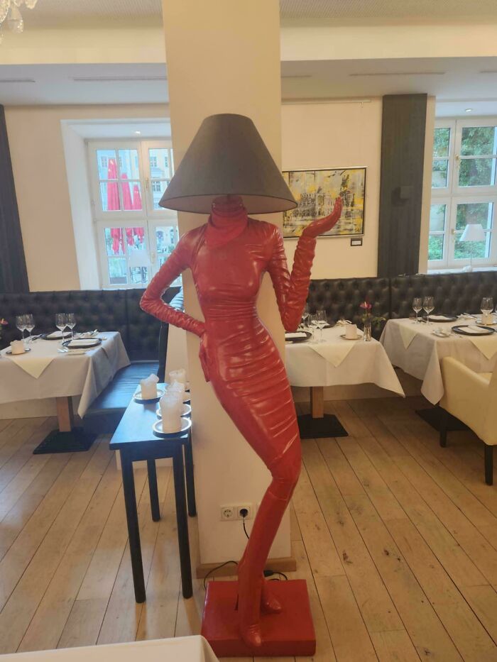 Red mannequin lamp with a dress-shaped body and lampshade head inside a restaurant, example of awful taste but great e*******n.