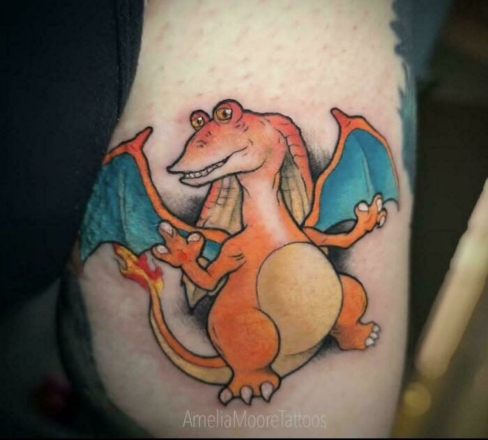 Tattoo of a poorly executed but funny dragon character in bright orange and blue colors showing awful taste but great e*******n.