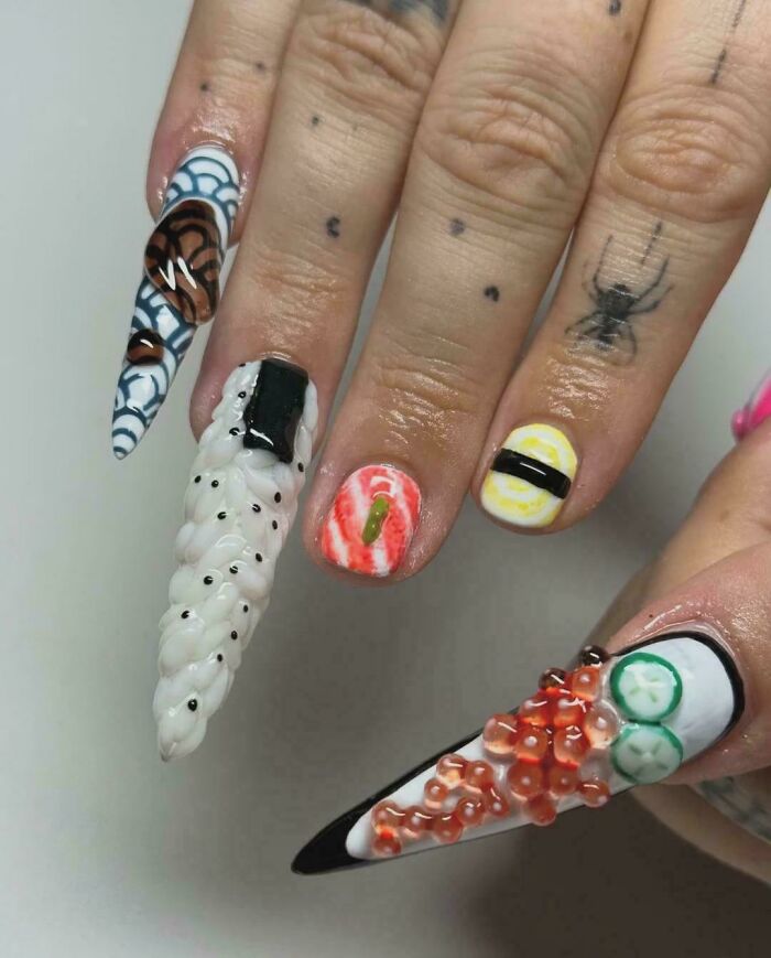 Close-up of nails with funny examples of awful taste but great e*******n, featuring sushi and spider-themed nail art designs.