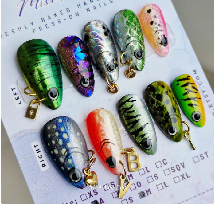 Colorful fish-shaped press-on nails with detailed patterns and charms, showcasing funny examples of awful taste but great e*******n.