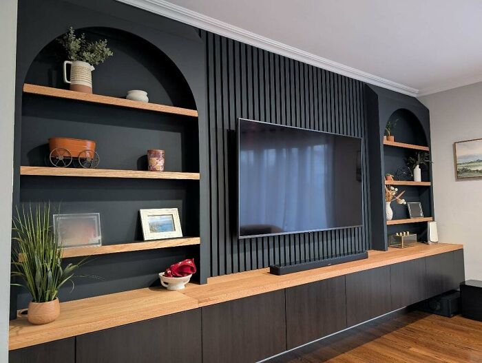 Modern living room entertainment unit with custom woodworker carved shelves and paneling around a wall-mounted TV.