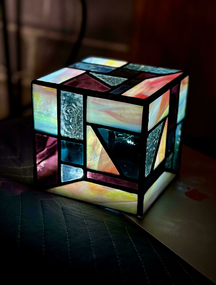 Stained glass cube lamp glowing in a dark room, showcasing unique home decoration with colorful glass panels.