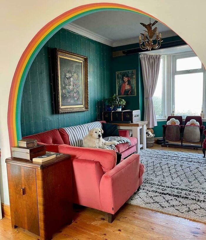 Cozy living room with coral sofa, teal walls, rainbow arch, vintage decor, and a dog relaxing, showcasing proud home decoration.