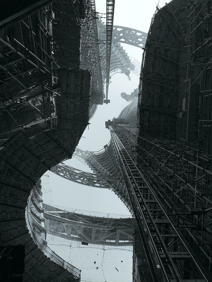 A low-angle view of extremely large, towering skyscrapers under construction, showing a scary and eerie perspective.
