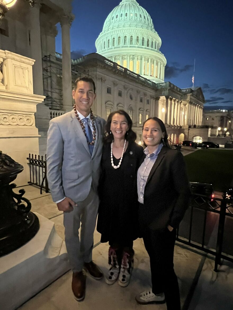 Three people smiling and posing at night outside a government building in a post from an interesting online community.