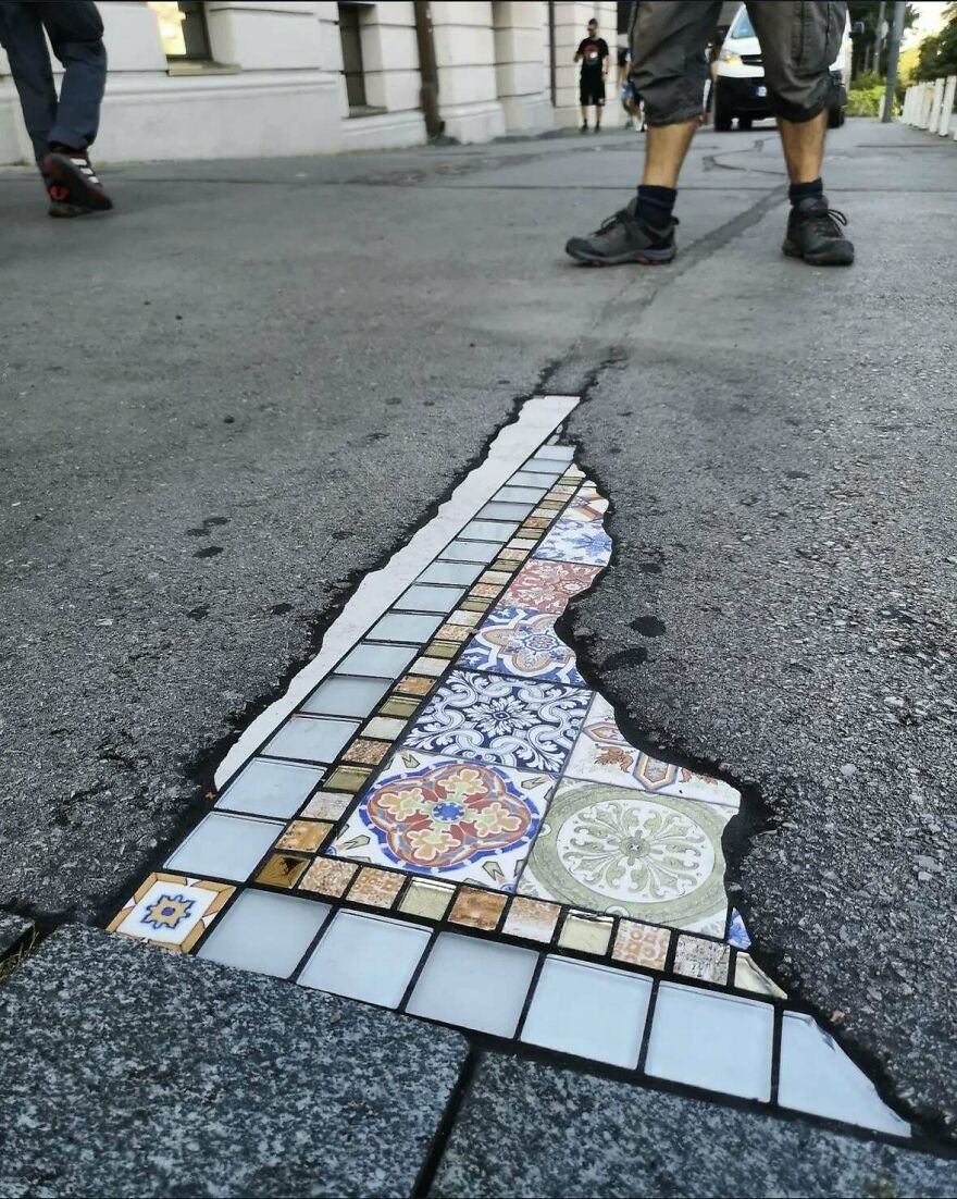 Street art revealing colorful mosaic tiles beneath c*****d asphalt, showcasing creative and interesting urban design.