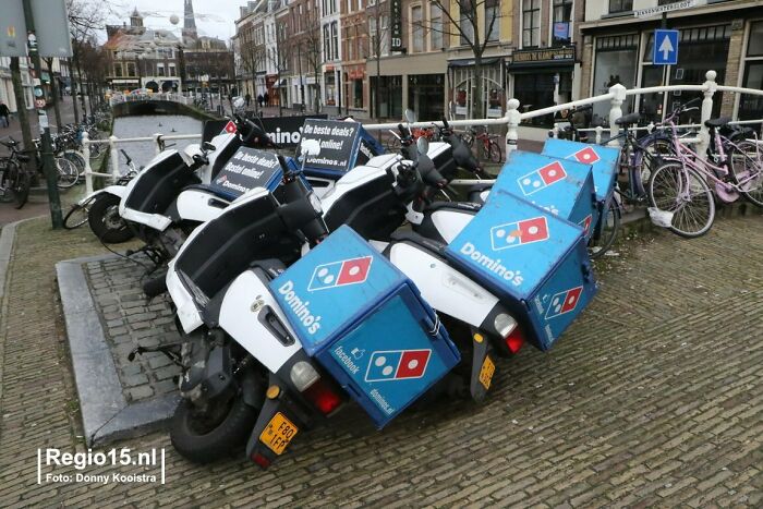 Scooters with Domino’s delivery boxes fallen over on a cobblestone street, showing nature’s unpredictable impact.