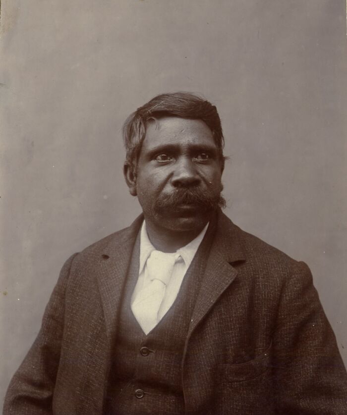 Portrait of an Indigenous Australian man from the 1900s wearing a suit, offering a rare glimpse into early Indigenous life.