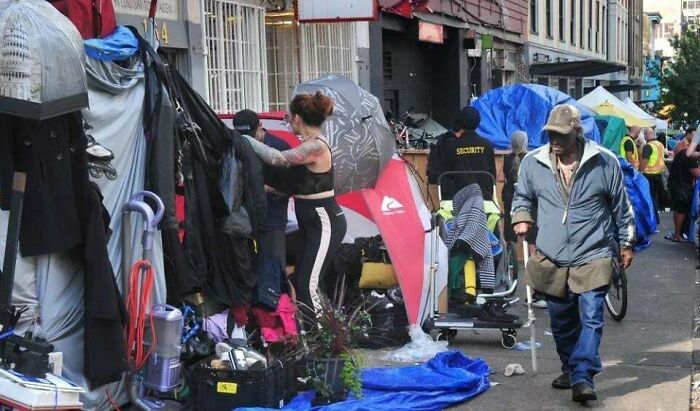 Homeless encampment on urban street with tents and belongings, illustrating effects of the $58 billion ghost city phenomenon.