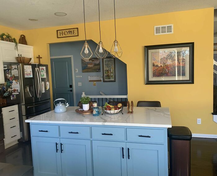 Bright kitchen corner with blue island and yellow walls, showcasing a decorated space people feel proud of in their homes.