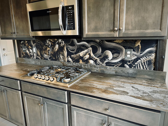 Kitchen corner with custom backsplash featuring skull and snake artwork, showcasing unique home decorating pride.