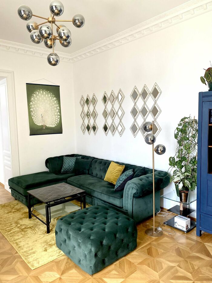 Living room corner with green velvet furniture, modern lighting, decorative mirrors, and plants showcasing home decorating pride.