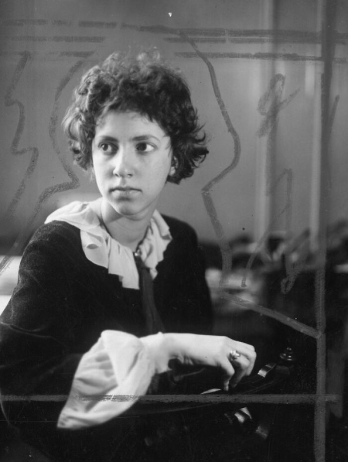 Young woman scientist with short curly hair sitting and looking to the side in a vintage Smithsonian portrait.