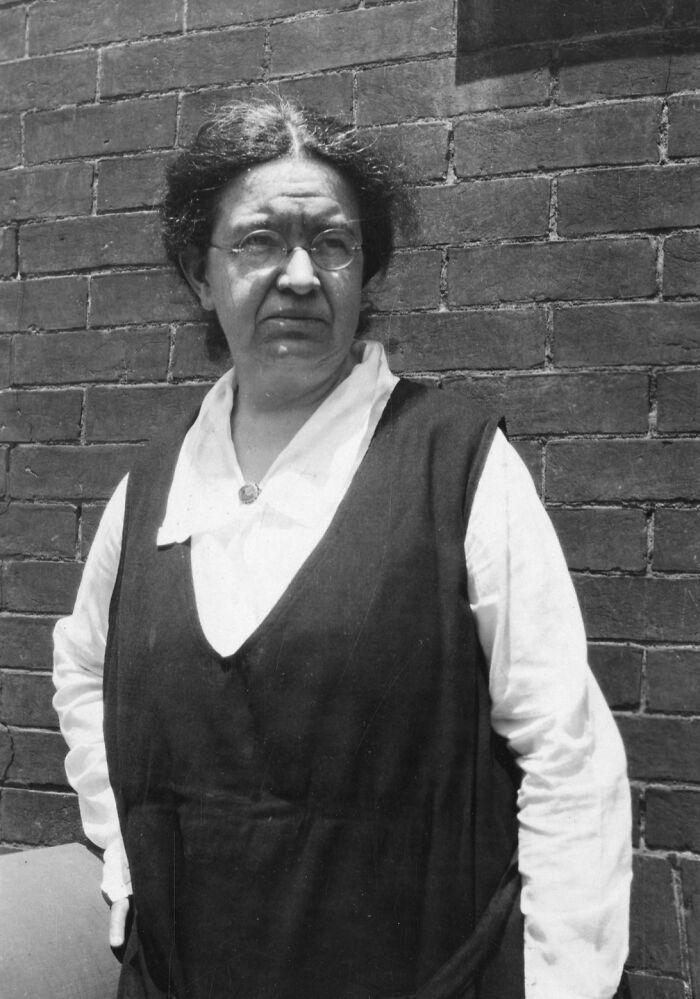 Black and white portrait of a woman scientist standing against a brick wall, representing remarkable women scientists.