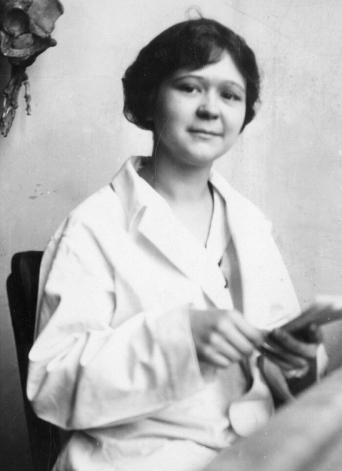 Black and white portrait of a woman scientist in a lab coat holding papers, featured in Smithsonian portraits collection.
