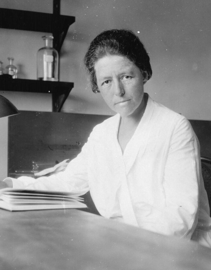 Female scientist in vintage lab coat reading documents, featured in Smithsonian portraits of remarkable women scientists.