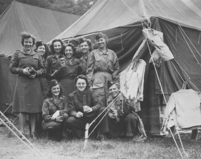 Group of women soldiers smiling and posing outside a military tent in a rare WWII photo during World War II.