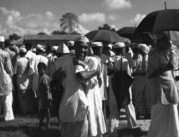 Group of men in traditional attire embracing and talking outdoors, captured in rare WWII photos from a historical moment.