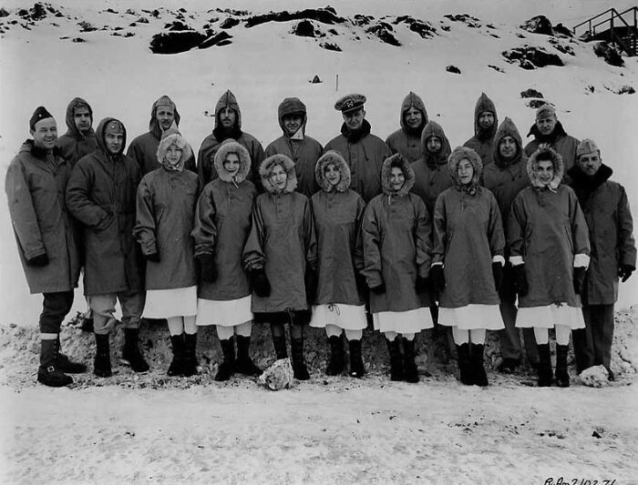 Group of WWII soldiers and nurses posing together outdoors in snowy terrain, a rare WWII photo showing winter military attire.