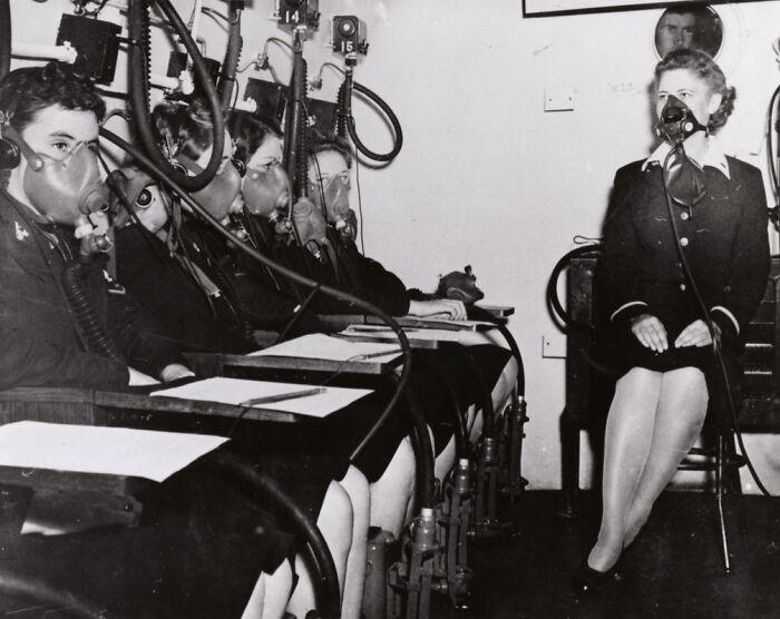 Women in WWII wearing gas masks during a military training exercise in a rare black and white historical photo.